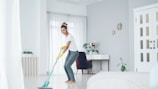 Woman happily mopping the floor in a bright room.