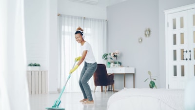 Woman happily mopping the floor in a bright room.