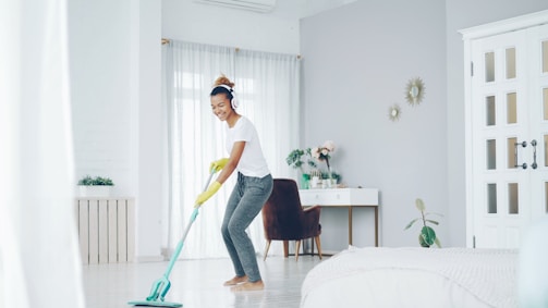 Woman happily mopping the floor in a bright room.