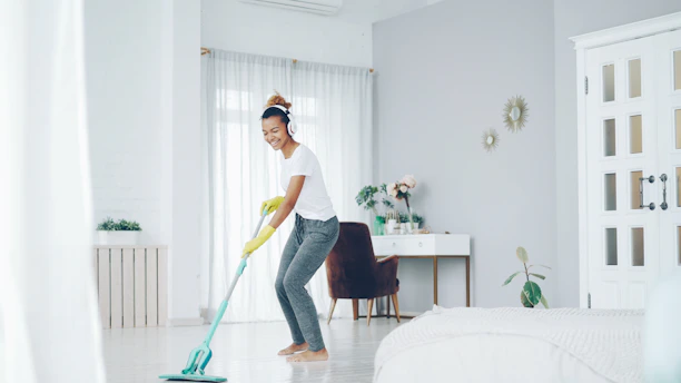 Woman happily mopping the floor in a bright room.