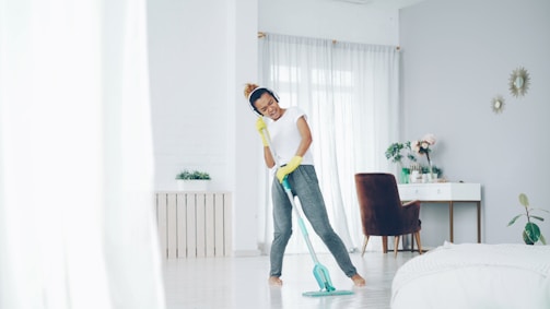Woman happily mopping a bright, modern living room.