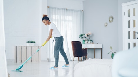A woman mops a bright, modern living room floor.
