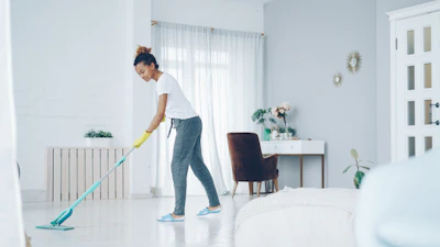 A woman mops a bright, modern living room floor.