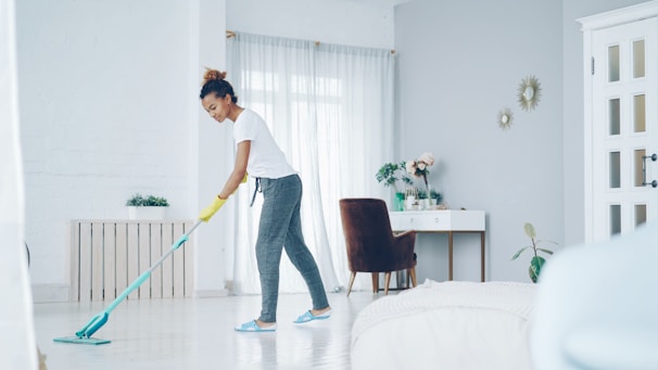 A woman mops a bright, modern living room floor.