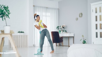 Woman with headphones cleaning floor while dancing