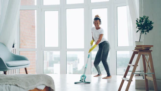 Woman cleaning floor with mop while wearing headphones