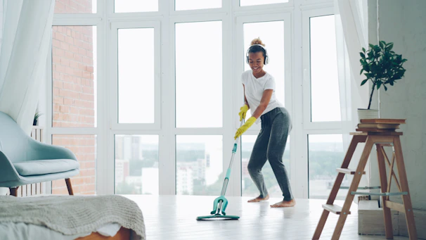 Woman cleaning floor with mop while wearing headphones