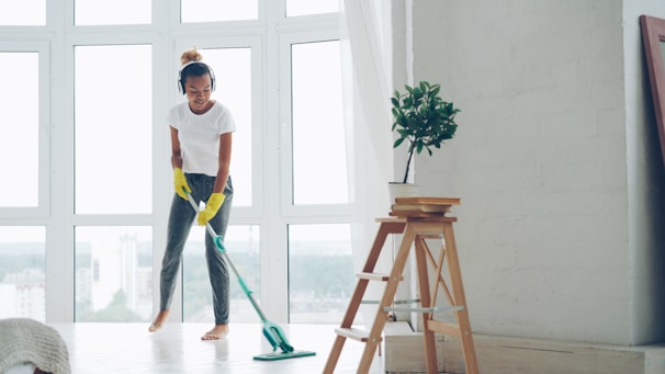 Woman mopping floor while listening to music.