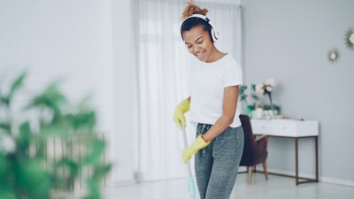 Woman with headphones cleaning floor with mop