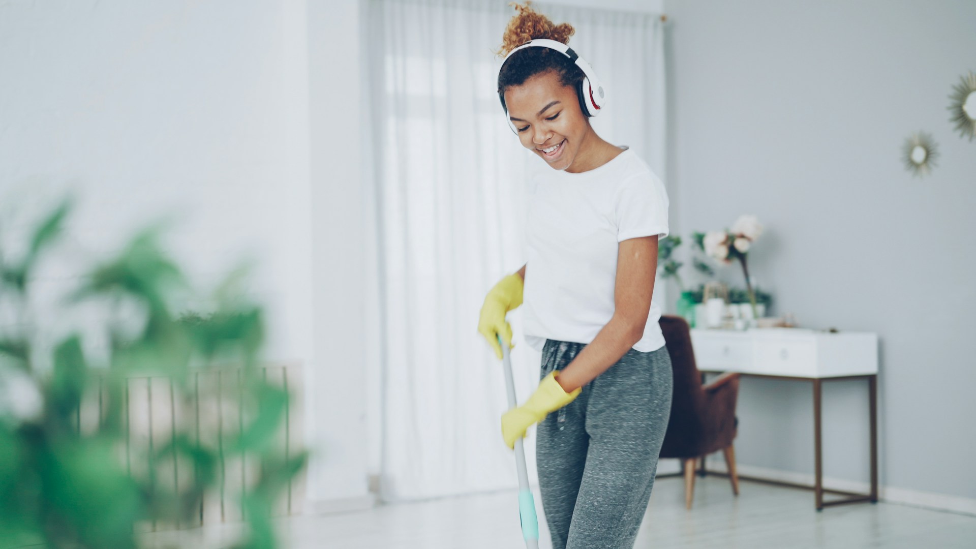 Woman with headphones cleaning floor with mop