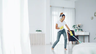 Woman with headphones cleaning and dancing happily