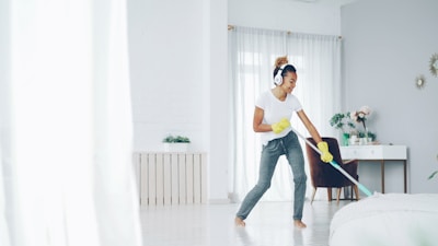 Woman with headphones cleaning and dancing happily