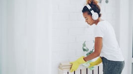 Young woman with headphones cleaning a shelf