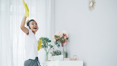 Woman with headphones happily cleaning with yellow gloves