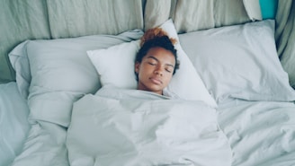 A young woman sleeping peacefully in a white bed.