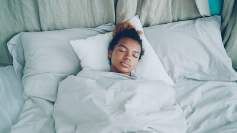 A young woman sleeping peacefully in a white bed.