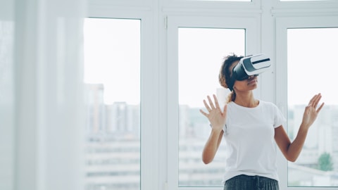 Woman using virtual reality headset indoors near window