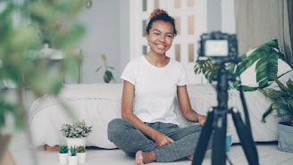 Young woman filming herself with a camera at home.
