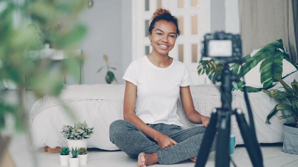 Young woman filming herself with a camera at home.
