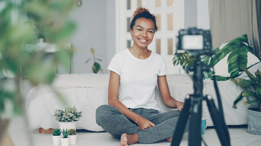 A person recording a video at a desk with a laptop, ring light, and notebook