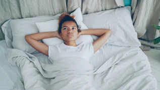 Young woman lying on a white bed