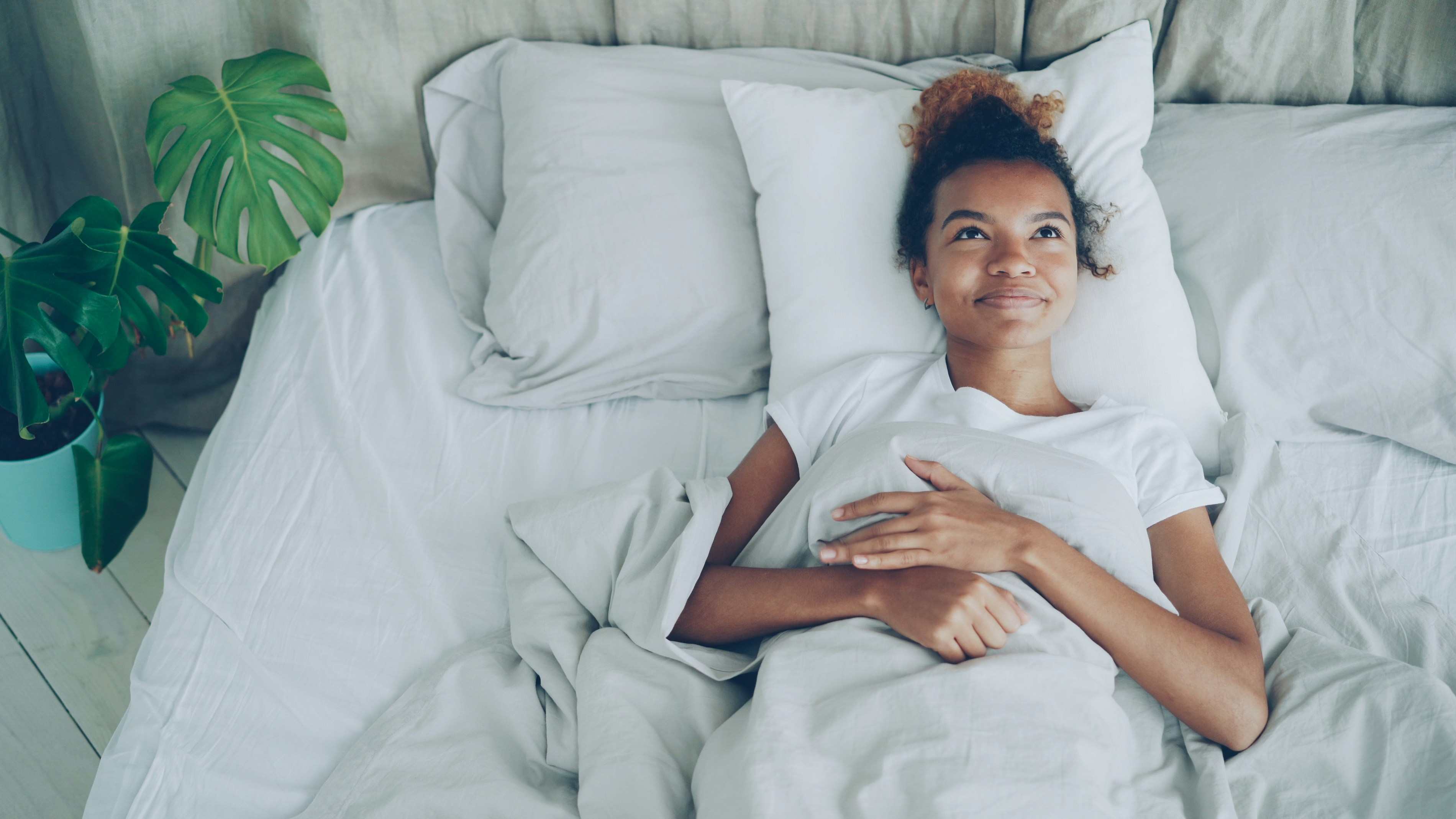 Happy young woman lying in bed