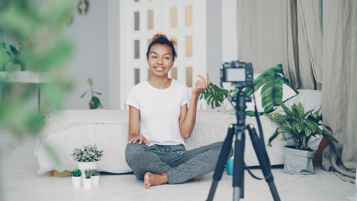 Young woman recording video with camera in room