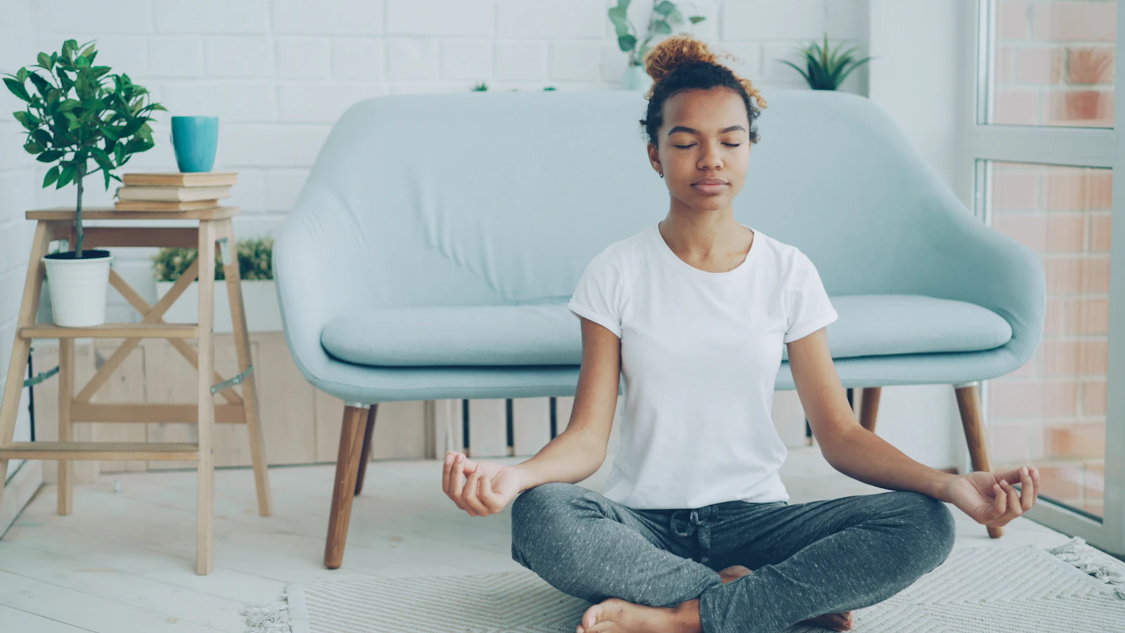 A woman practicing calm seated meditation at home
