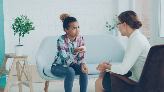 Therapist talking to a young girl on couch.