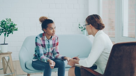 Therapist talking to a young woman on couch.