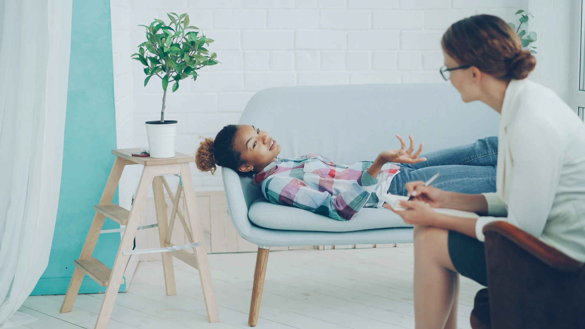 A young girl talks to a therapist on a couch.