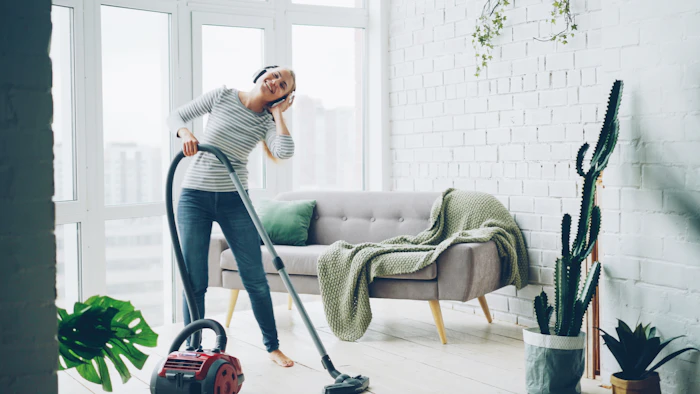 Household cleaner tidying a bright modern living room