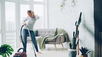 Woman happily vacuuming a bright, modern living room.