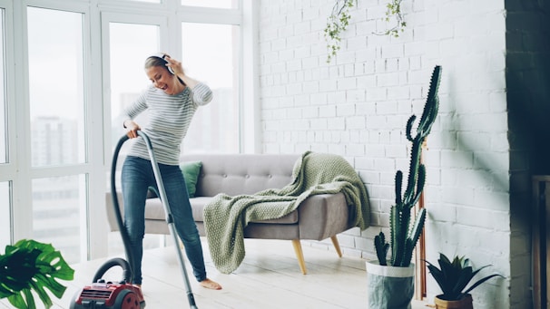 Woman happily vacuuming a bright, modern living room.
