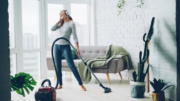 Woman happily vacuuming living room while listening to music.