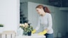 Woman in yellow gloves cleaning a table