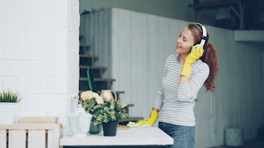 Woman with headphones cleaning and enjoying music.