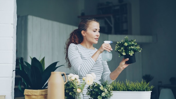 Woman watering plants on a balcony.
