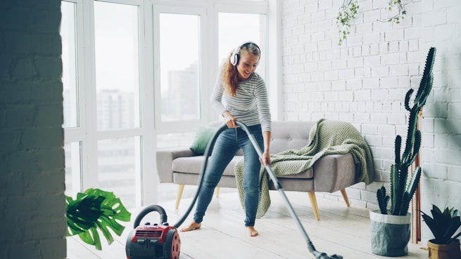 Woman vacuuming floor while listening to music.