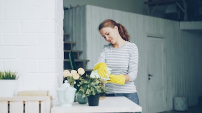 Woman wearing yellow gloves tending to potted plants.