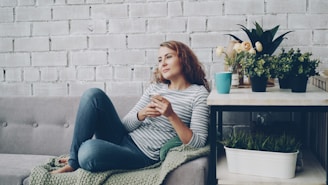 Woman relaxing on sofa with phone and coffee.