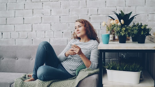 Woman relaxing on sofa with phone and coffee.