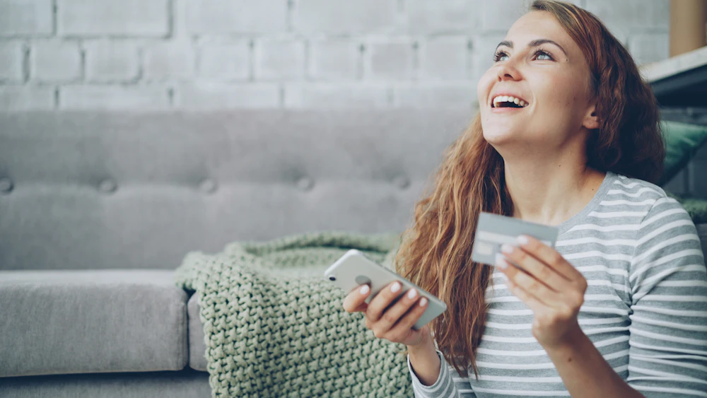 A woman using her phone and debit card