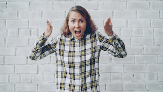 Woman with hands raised shouting in frustration.