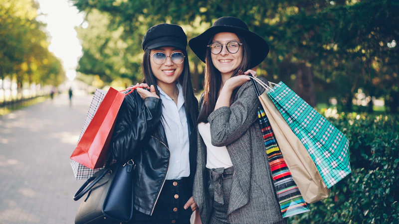 Two smiling women holding shopping bags outdoors