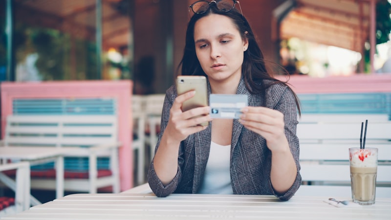 Person using financial app on smartphone with coffee