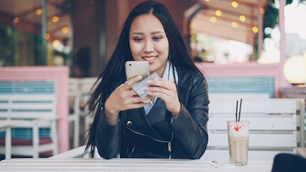 Young woman using smartphone at outdoor cafe table