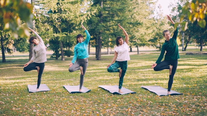 Four people practice yoga in a park.
