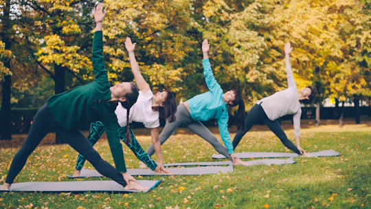 Four people practicing yoga in a park.