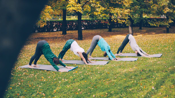 Four women practice downward-facing dog yoga pose outdoors